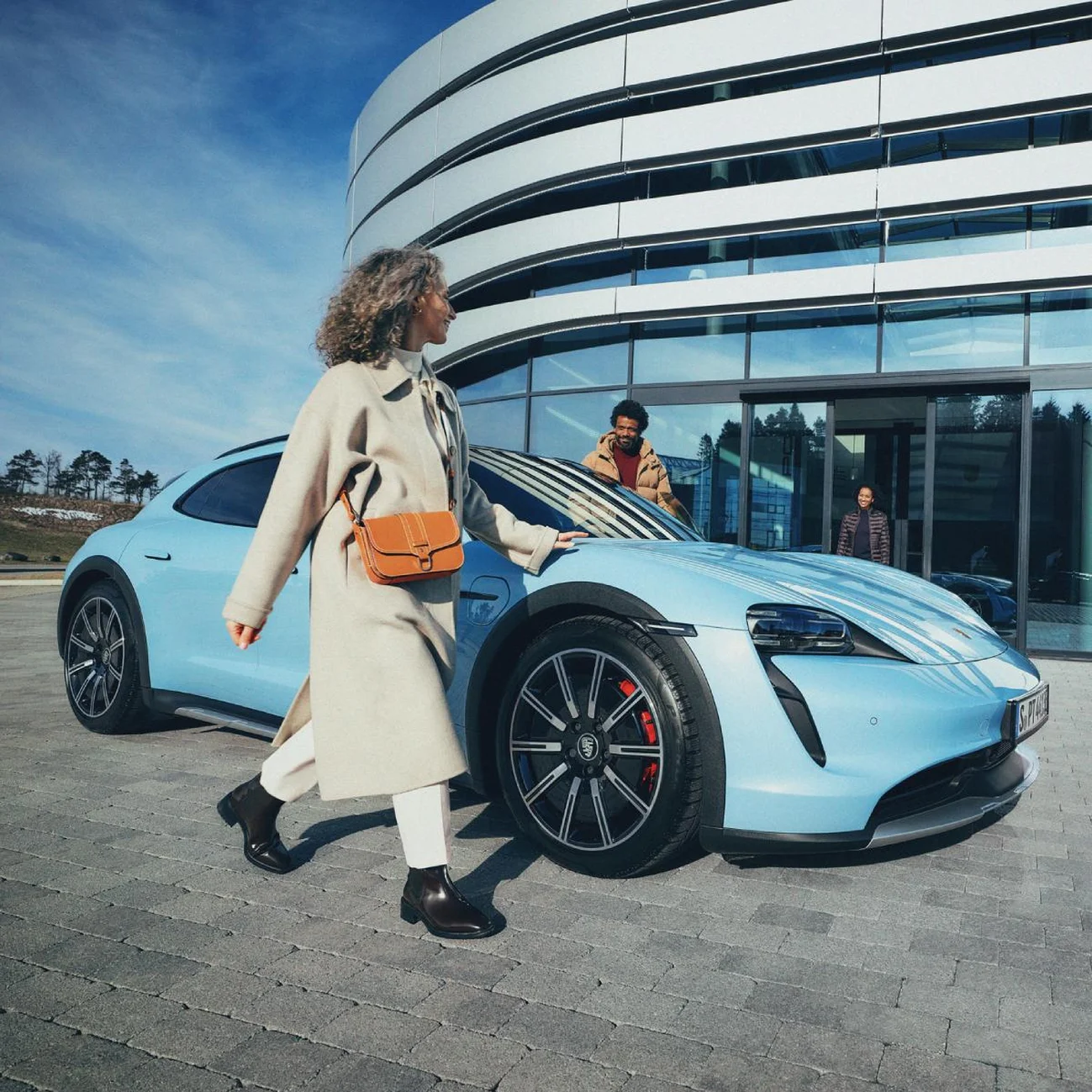 Customer arriving at a Porsche Centre, walking past a parked Porsche outside.