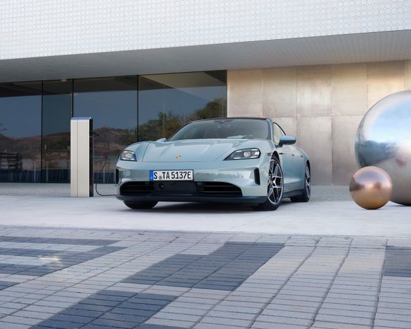 A Porsche Taycan parked outside in front of a modern building.