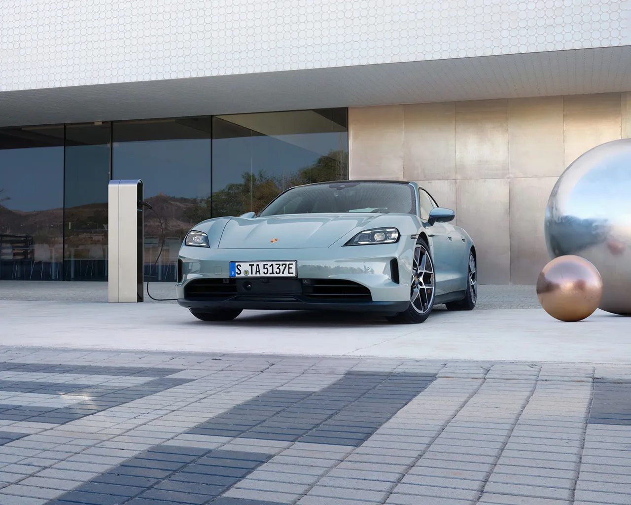 A Porsche Taycan parked outside in front of a modern building.