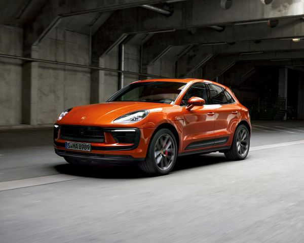 A Porsche all-electric Macan driving down a road in an urban scenario.