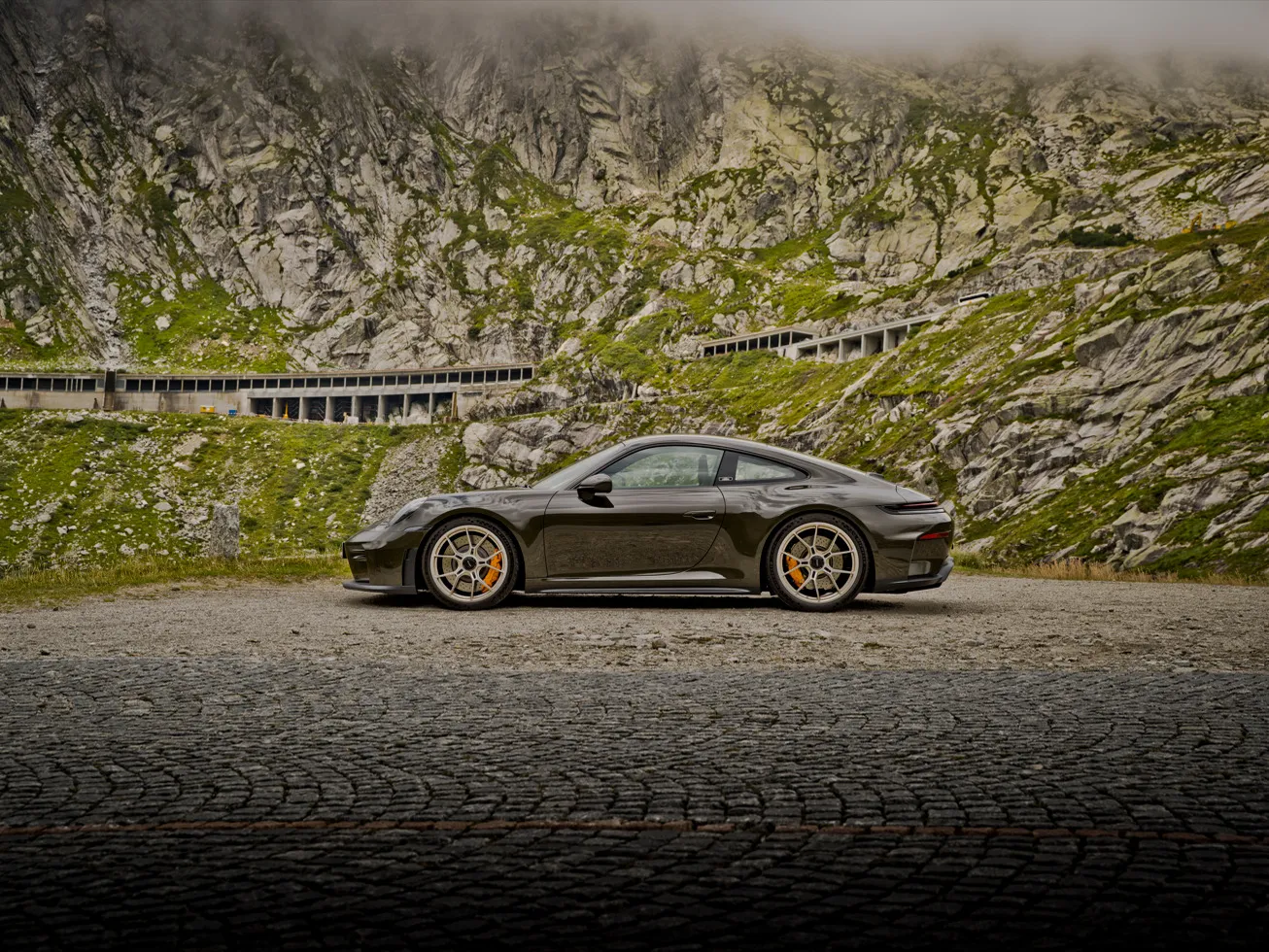 Ein 911 GT3 mit Touring-Paket auf einer Passstraße in einer alpinen Berglandschaft mit felsigen Hängen.