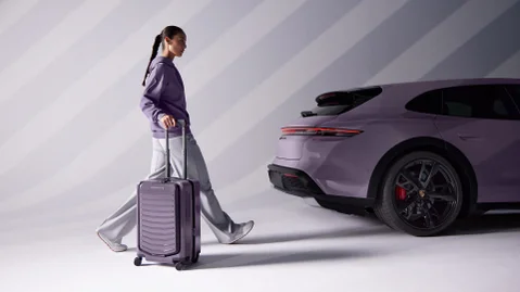 Vrouw met Porsche trolley voor een Porsche Taycan.