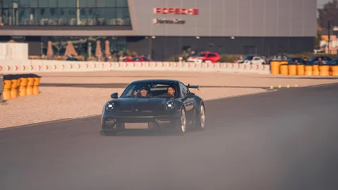 A Porsche racing model driving in a circuit.