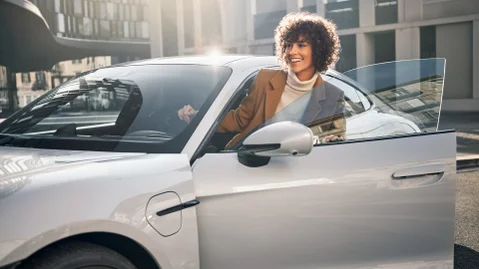 A woman partially outside of a Porsche car.
