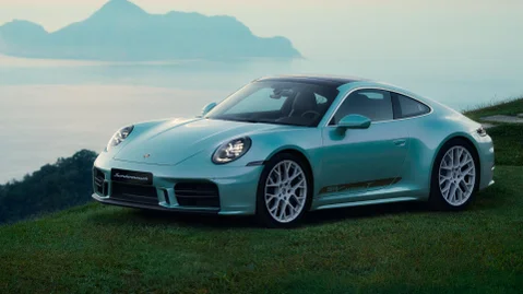 A blue 911 Carrera T Formosa on the grass in front of the coastline.