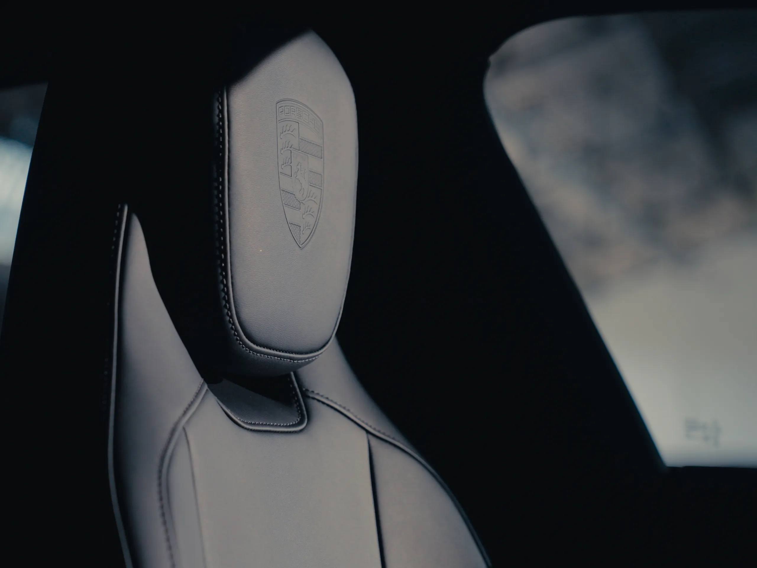 Close up of a car seat with a Porsche crest on the headrest.
