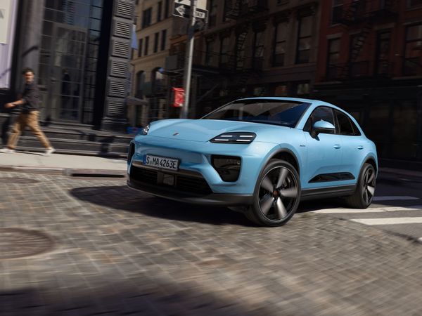 Front shot of a Frozen Blue Metallic Macan Electric driving through the city.