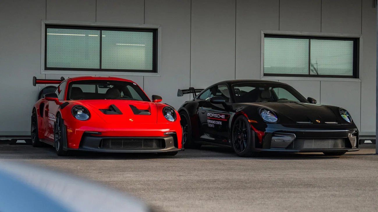 Two Porsche sports cars parked, one red and one black.